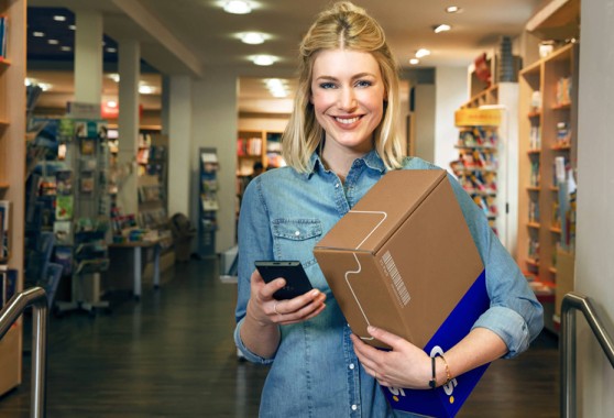 Smiling woman holding parcel GLS France in Parcel Shop