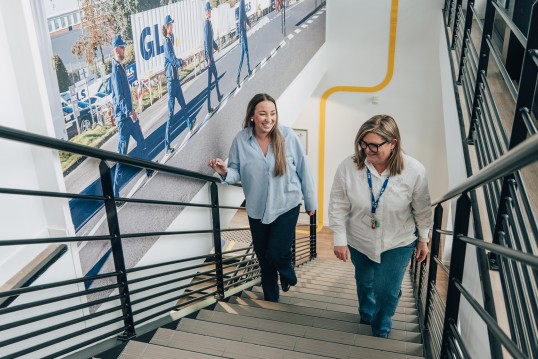 Collaboratrices dans les bureaux d'une entreprise de logistique, montant un escalier en équipe.