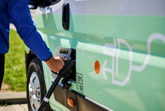 Fourgonnette électrique de service branchée à une borne de recharge, illustrant une livraison à plus faibles émissions.