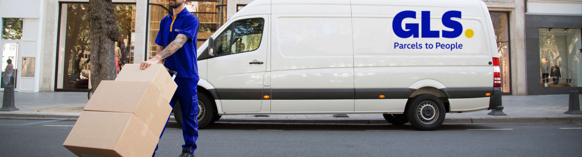 Un livreur transporte des colis devant sa camionnette