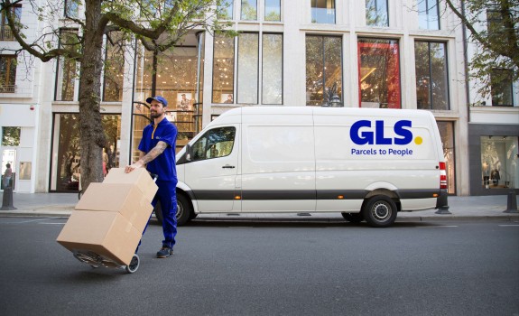 Un livreur transporte des colis devant sa camionnette